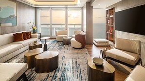 A modern living room with a sofa, armchairs, a coffee table, and a flat-screen TV. - Sheraton Grand Tel Aviv (Tel Aviv)