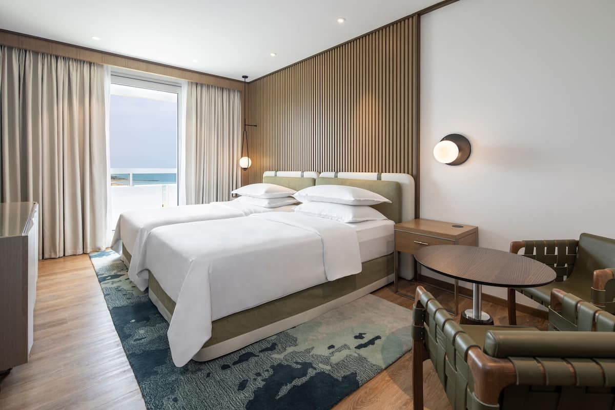 Una habitación de hotel moderna con una cama grande, una mesita y un espacio para sentarse.