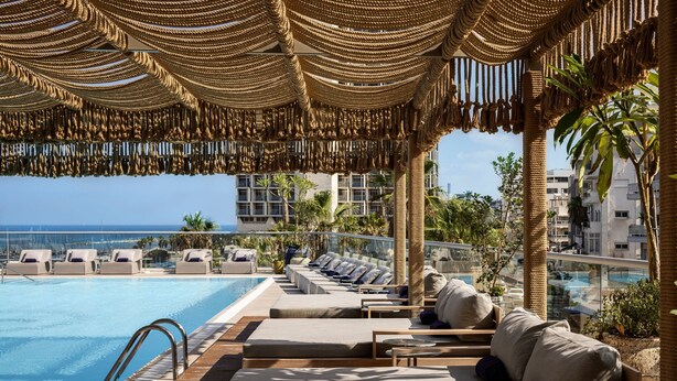 A poolside lounge area with sun loungers and a view of the ocean. - Sheraton Grand Tel Aviv (Tel Aviv)