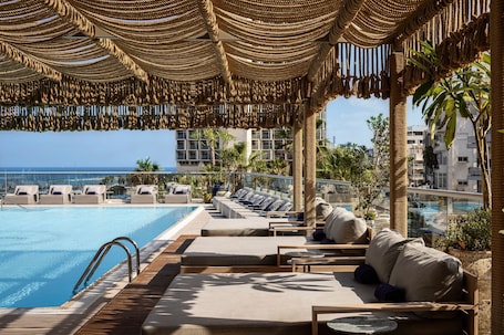 Una piscina al aire libre, sombrillas, sillones reclinables de piscina. Sheraton Grand Tel Aviv
