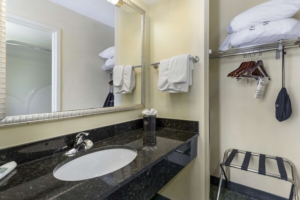 A hotel bathroom with a sink, mirror, towel rack, and a towel drying rack.