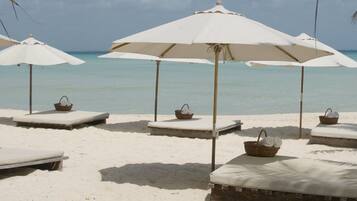 Sable blanc, chaises longues, parasols, serviettes de plage