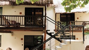 Un edificio de varios niveles con escaleras, zona de estar al aire libre y construcciones con tejados de paja.