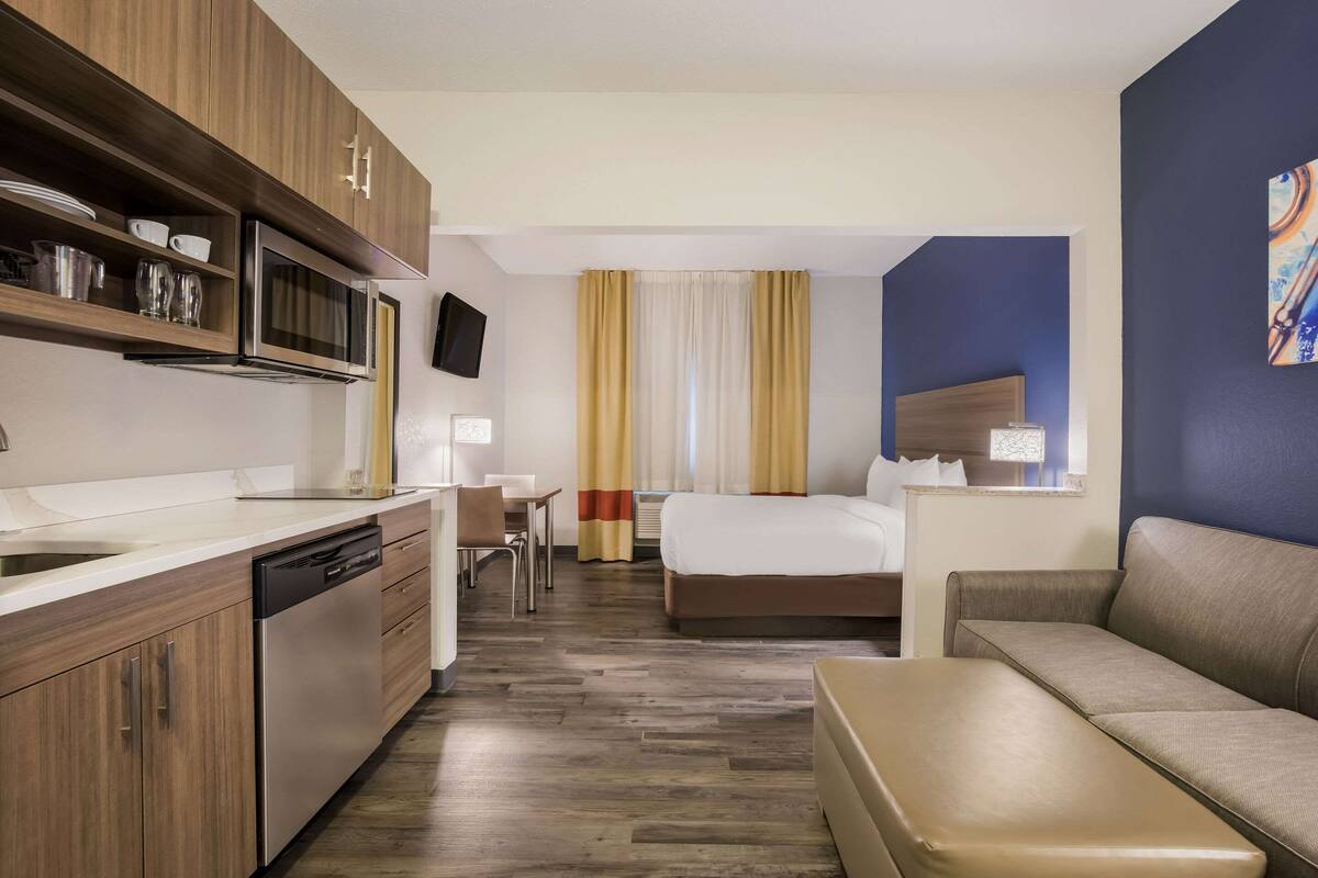 Una camera d'albergo con angolo cottura, un letto, un divano e un tavolino.