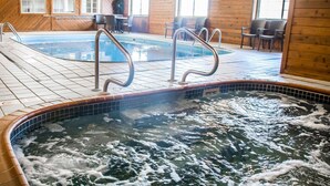 An indoor swimming pool with a hot tub, wooden walls, and tiled flooring.