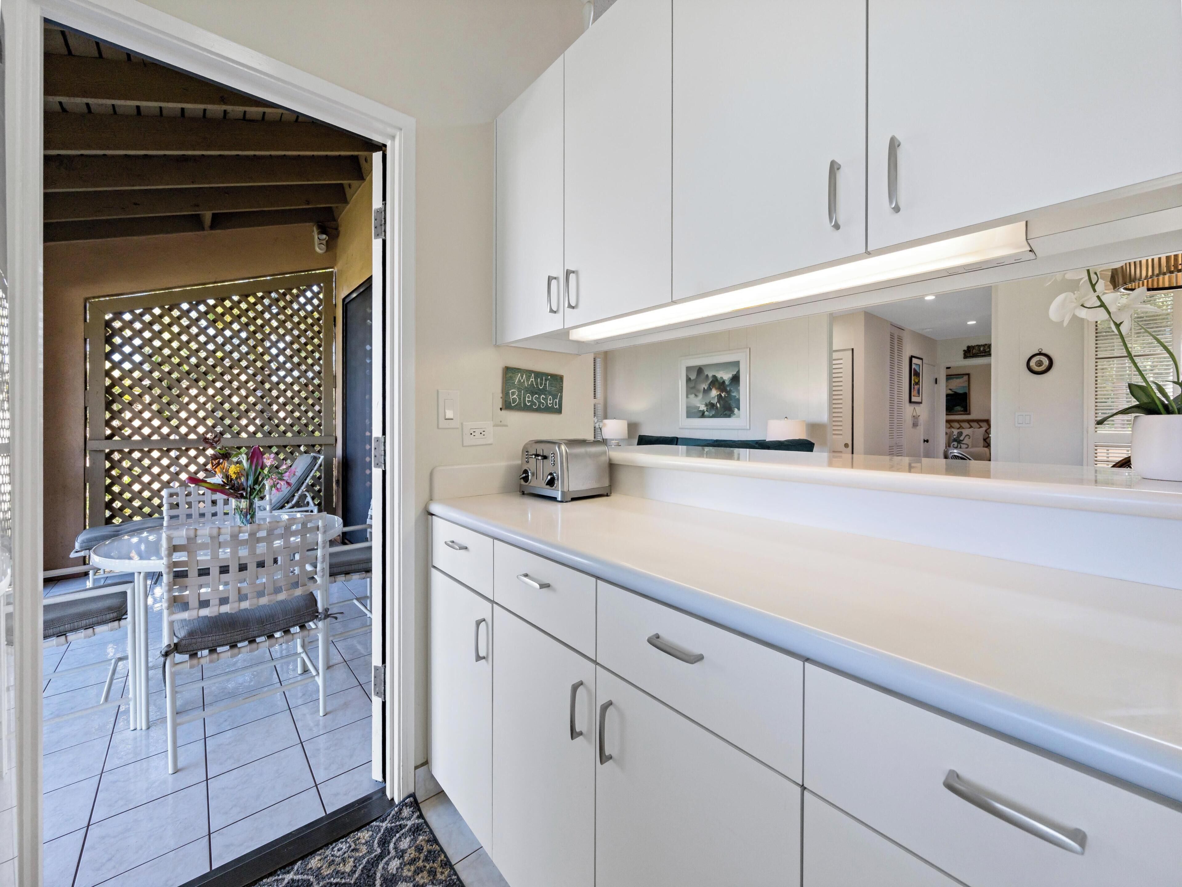 A modern kitchen with white cabinets, a built-in toaster, and a dining area with a table and chairs.