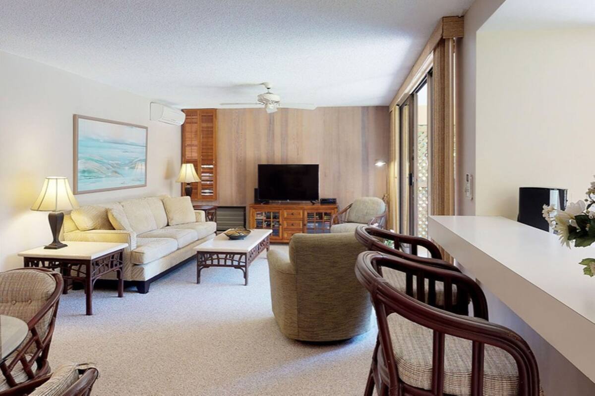 Una sala de estar moderna con un sofá, sillones, una mesa de centro, un televisor y una estantería.