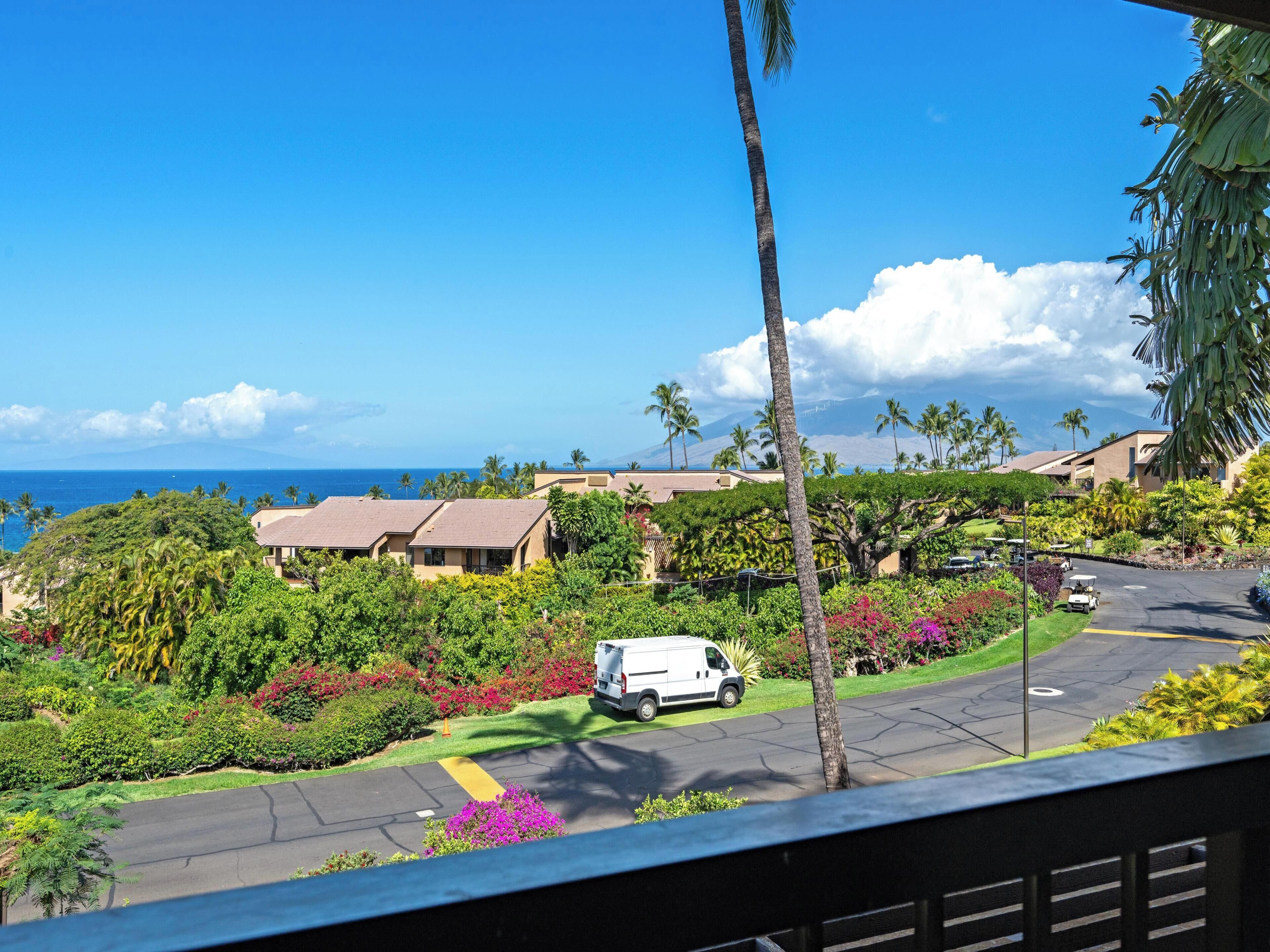 A residential area with houses, a parking lot, and a view of the ocean.