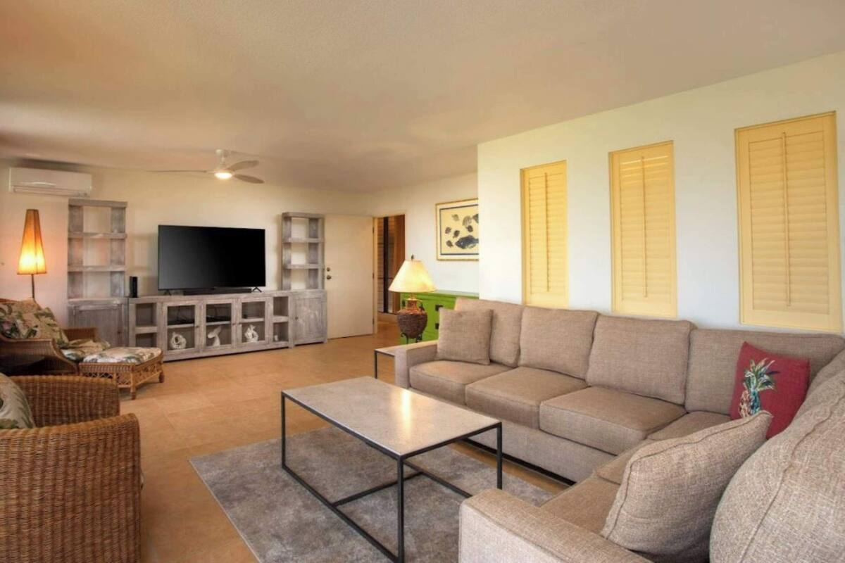Una sala de estar con sofá, mesa de centro, televisor y lámpara.