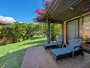 A patio with two lounge chairs, a pergola with flowering vines, and a view of a lush garden. - Wailea Ekahi - CoralTree Residence Collection (Kihei)