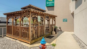 Un kiosque en bois, avec un hydrant bleu devant, situé à côté d’un bâtiment portant l’enseigne « Quality Inn by Choice Hotels ».