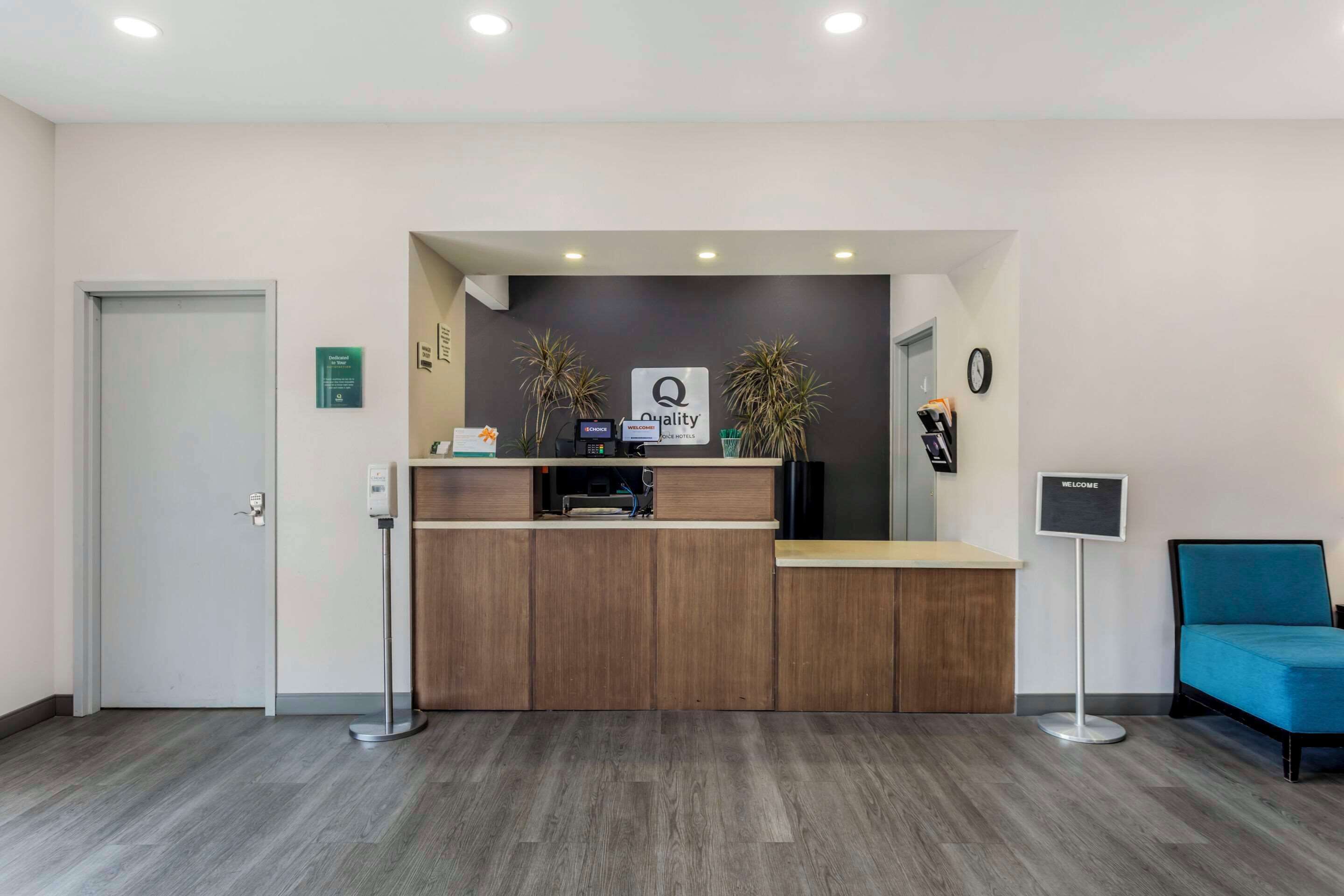 A reception area with a wooden desk, a reception counter, a blue chair, and a sign that says "WELCOME".