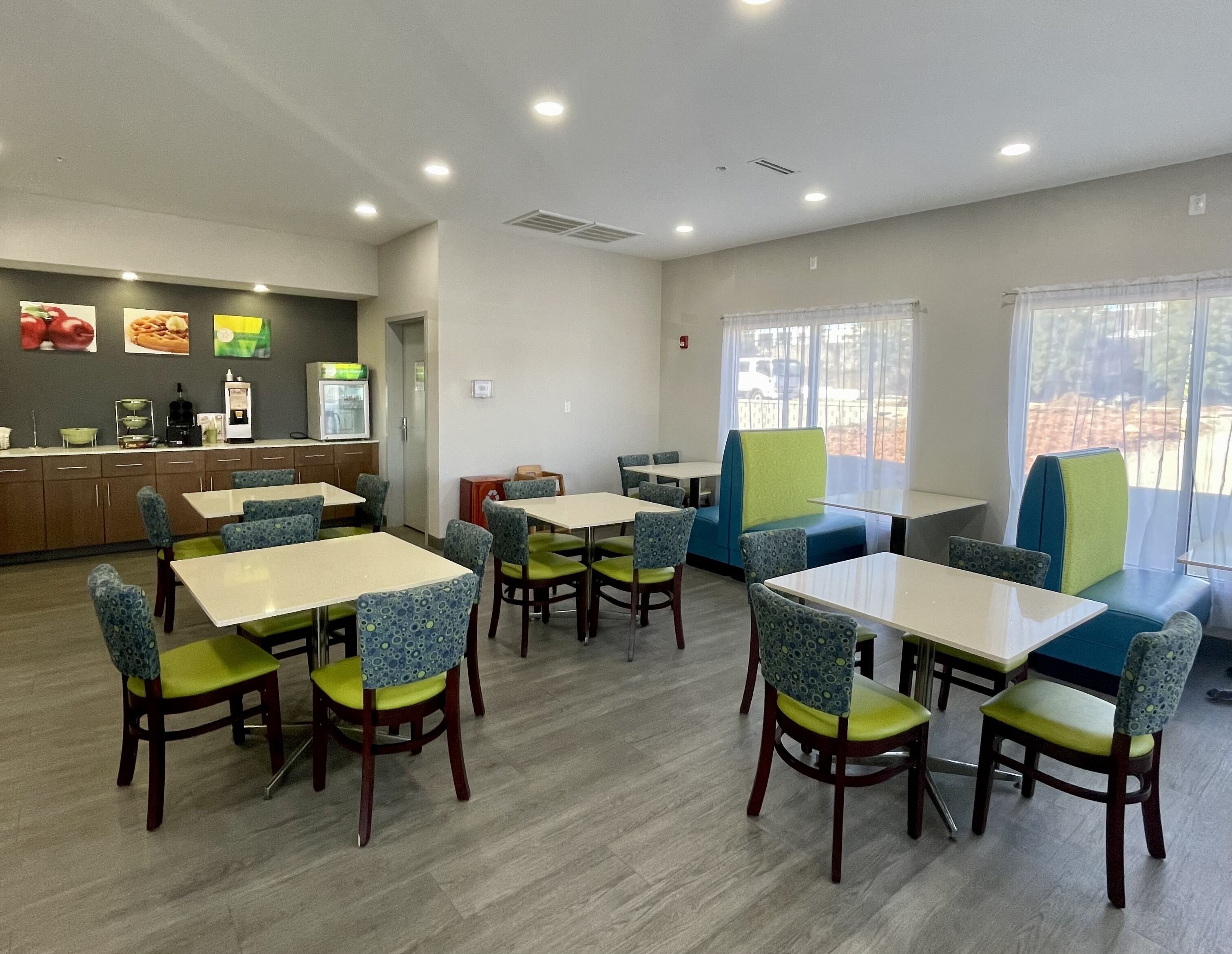 A restaurant with tables and booths, a kitchen area, and a view of the outdoors.