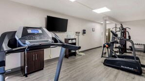 Une salle de sport équipée de tapis de course, d’un vélo d’appartement et d’une machine de musculation.