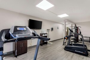 Un gimnasio con cintas de correr, una bicicleta estática y una máquina de pesas.