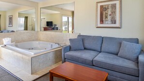 Ein modernes Badezimmer mit einer Badewanne, einem grauen Sofa und einem Holztisch.