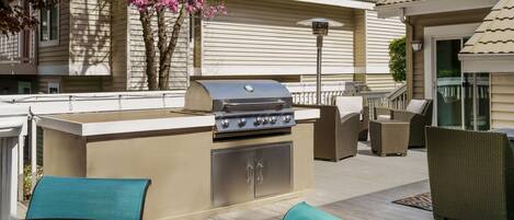 An outdoor kitchen with a grill, built-in cabinets, and outdoor furniture.