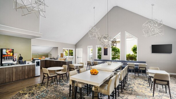 A spacious kitchen with modern appliances, a dining area with multiple tables and chairs, and a large window providing a view of the outdoors.