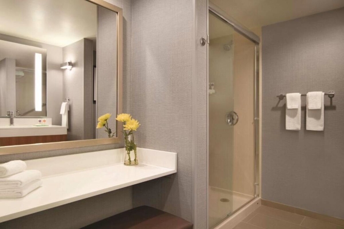 Een moderne badkamer met een glazen douche, een witte wastafel en een spiegel.