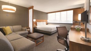 Una habitación de hotel con cama, sofá, escritorio y televisión.