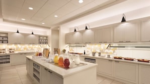 Una cocina moderna con armarios blancos, una isla central con bebidas e iluminación colgante.