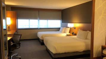 Una habitación de hotel con dos camas, un escritorio, una silla y una ventana.