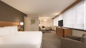 Ein Hotelzimmer mit einem großen Bett, einem Schreibtisch, einem Sofa und einem Fernseher.