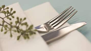 Un tenedor y un cuchillo sobre una servilleta blanca, con una planta verde de fondo.
