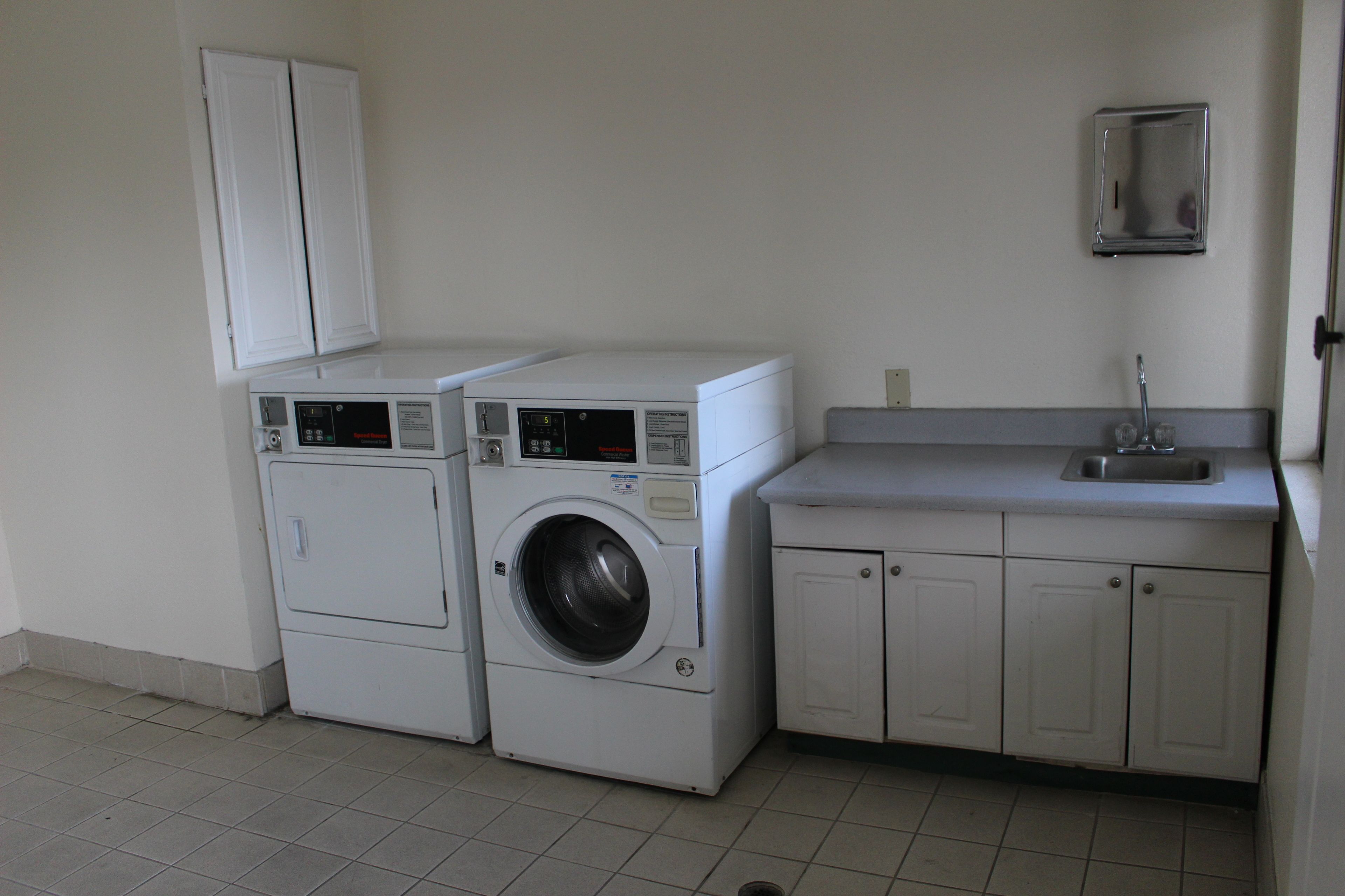 A laundry area with a washing machine and dryer, a sink, and cabinets.