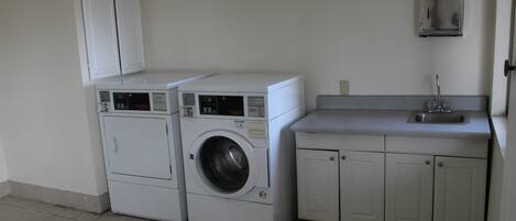 A laundry area with a washing machine and dryer, a sink, and cabinets.