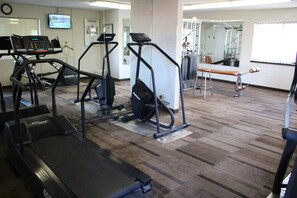 A gym with treadmills, elliptical machines, and a bench. - Days Inn & Suites by Wyndham Sunnyvale (Sunnyvale)
