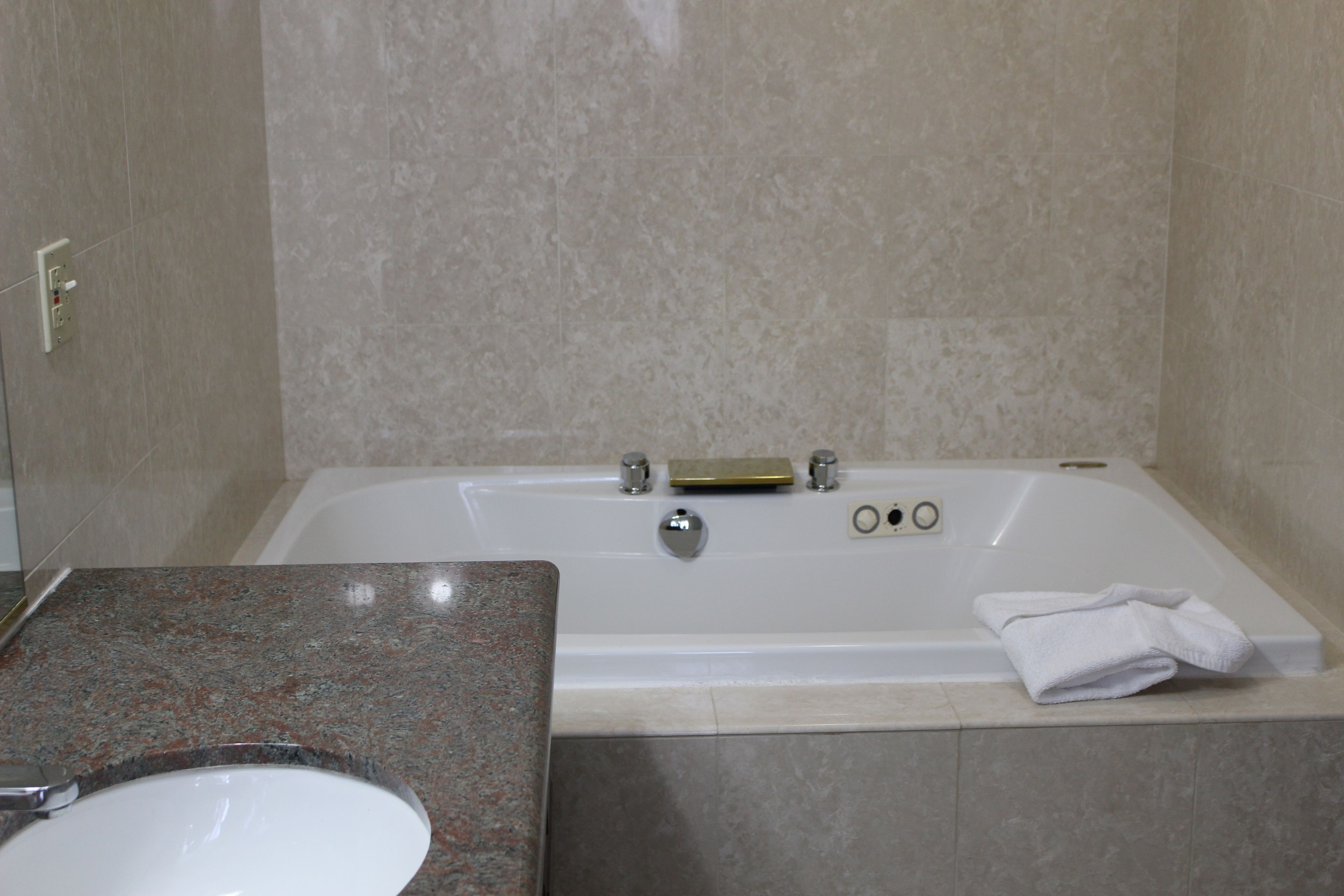 A bathroom with a bathtub, a sink, and a towel on the side.