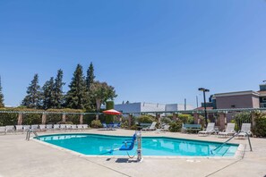 Una piscina al aire libre, sillones reclinables de piscina