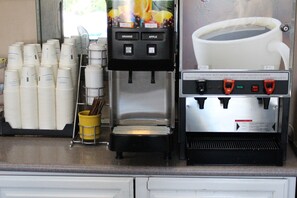 A coffee machine with buttons for orange and apple, and a coffee pot. - Days Inn & Suites by Wyndham Sunnyvale (Sunnyvale)
