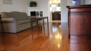 A living room with a patterned sofa, a wooden coffee table, and a wooden cabinet. - Days Inn & Suites by Wyndham Sunnyvale (Sunnyvale)