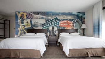 A hotel room with two beds, a cityscape mural on the wall, and a wooden floor.