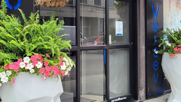 The exterior of the Hotel Versey with a black awning, a glass entrance door, and potted plants with red and white flowers. - Hotel Versey Chicago Lincoln Park (Chicago)