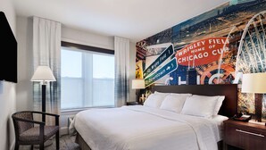 A hotel room with a large bed, a chair, a nightstand, and a wall with a Chicago Cubs mural. - Hotel Versey Chicago Lincoln Park (Chicago)