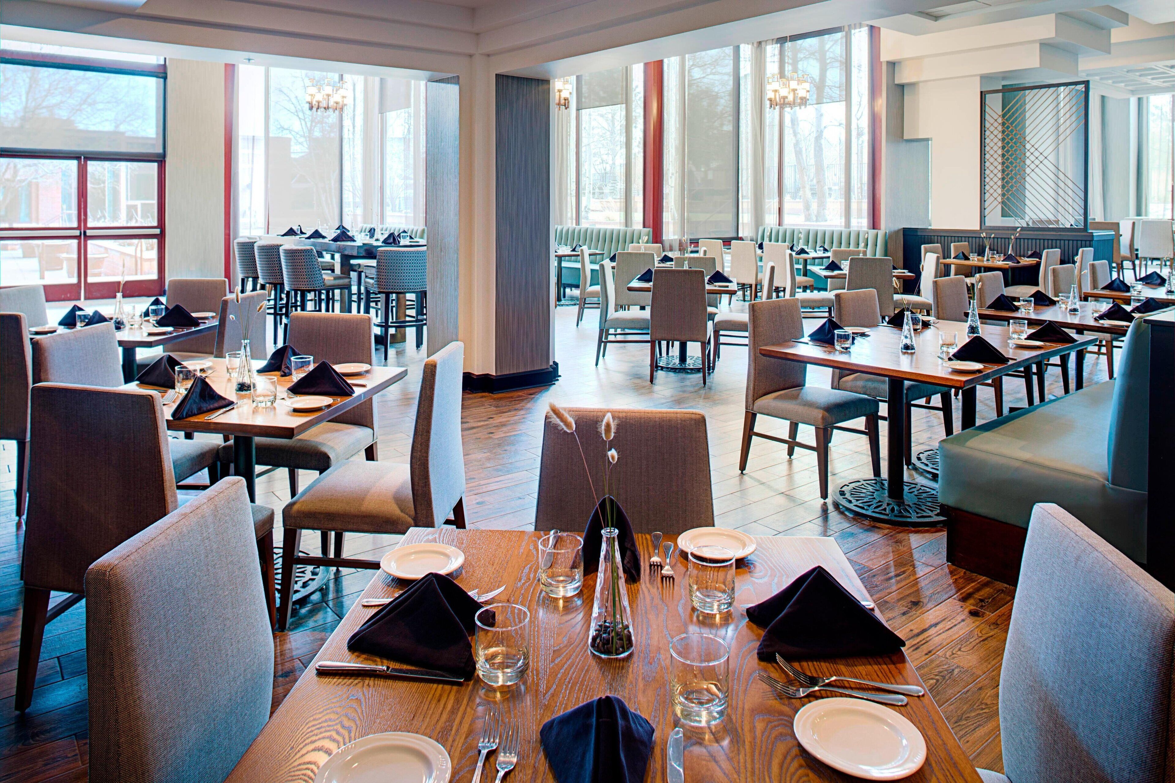 A spacious restaurant with multiple dining areas, large windows, and modern decor.