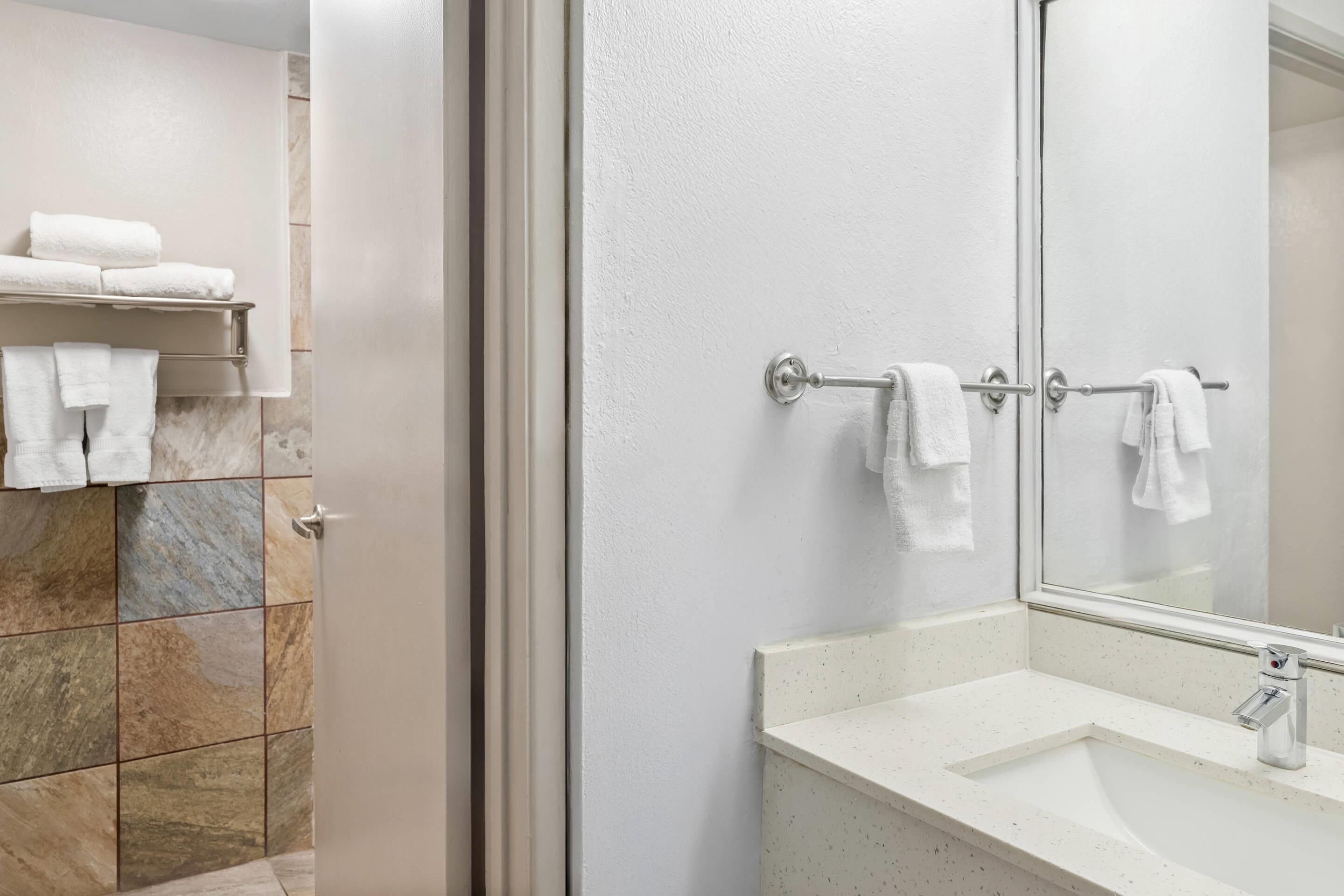 A bathroom with a white sink, a mirror, and a towel rack with towels.