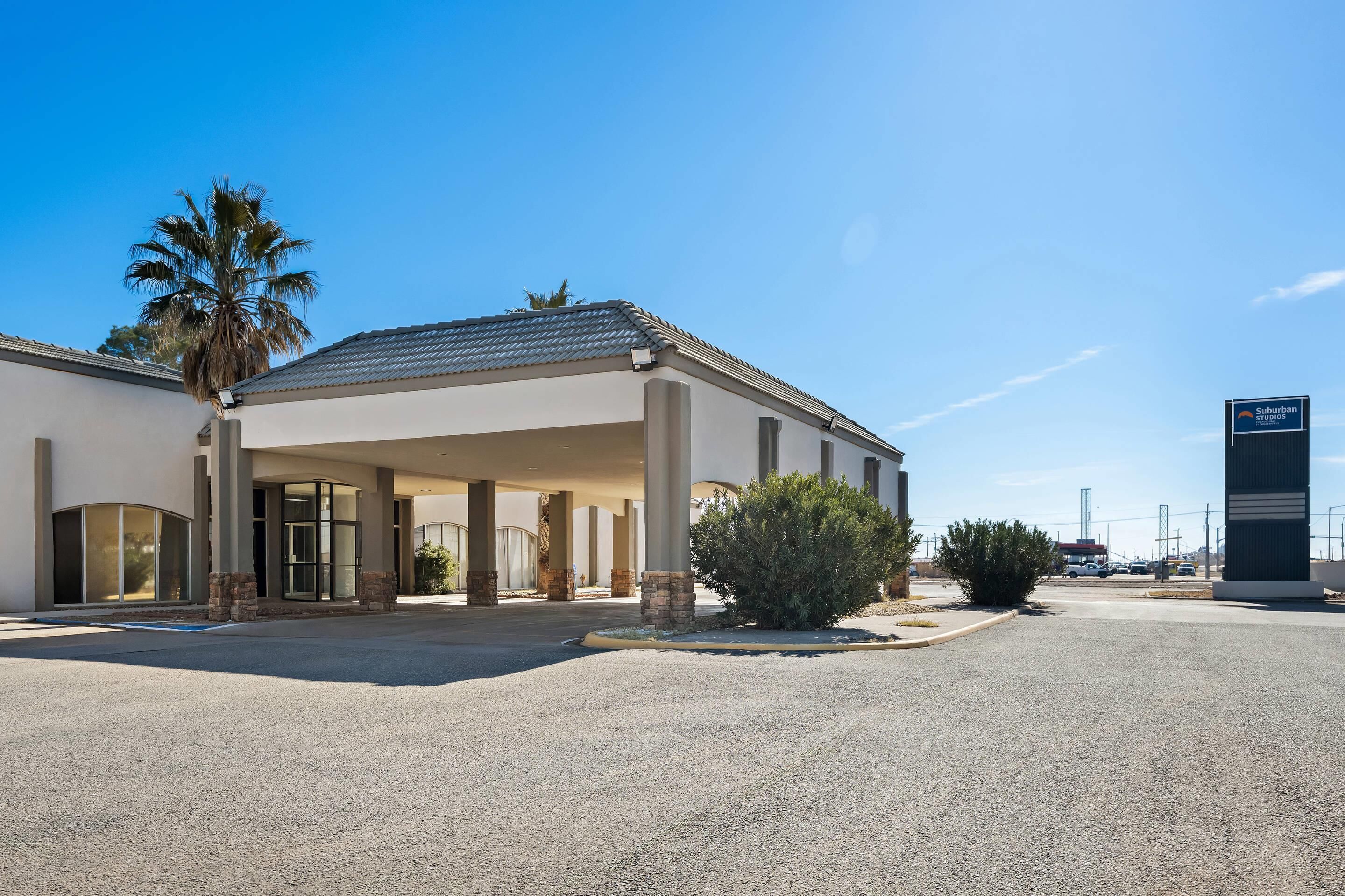 Un hôtel doté d’une entrée abritée, de palmiers et surplombant un ciel d’un bleu limpide.