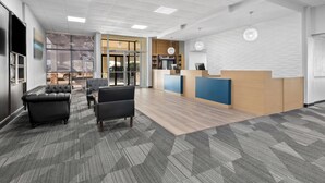 A modern office space with a reception desk, seating area, and large windows. - Suburban Studios Pecos (Pecos)