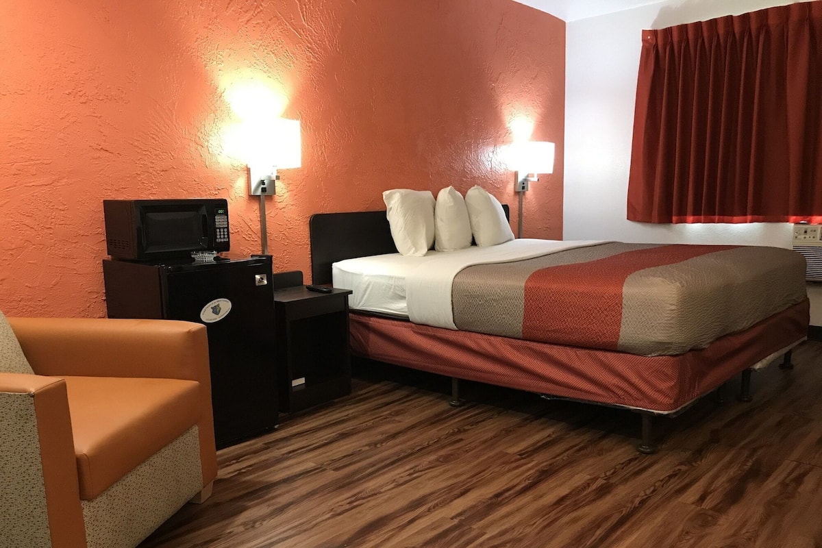 A hotel room with a bed, a desk, a chair, and a television.