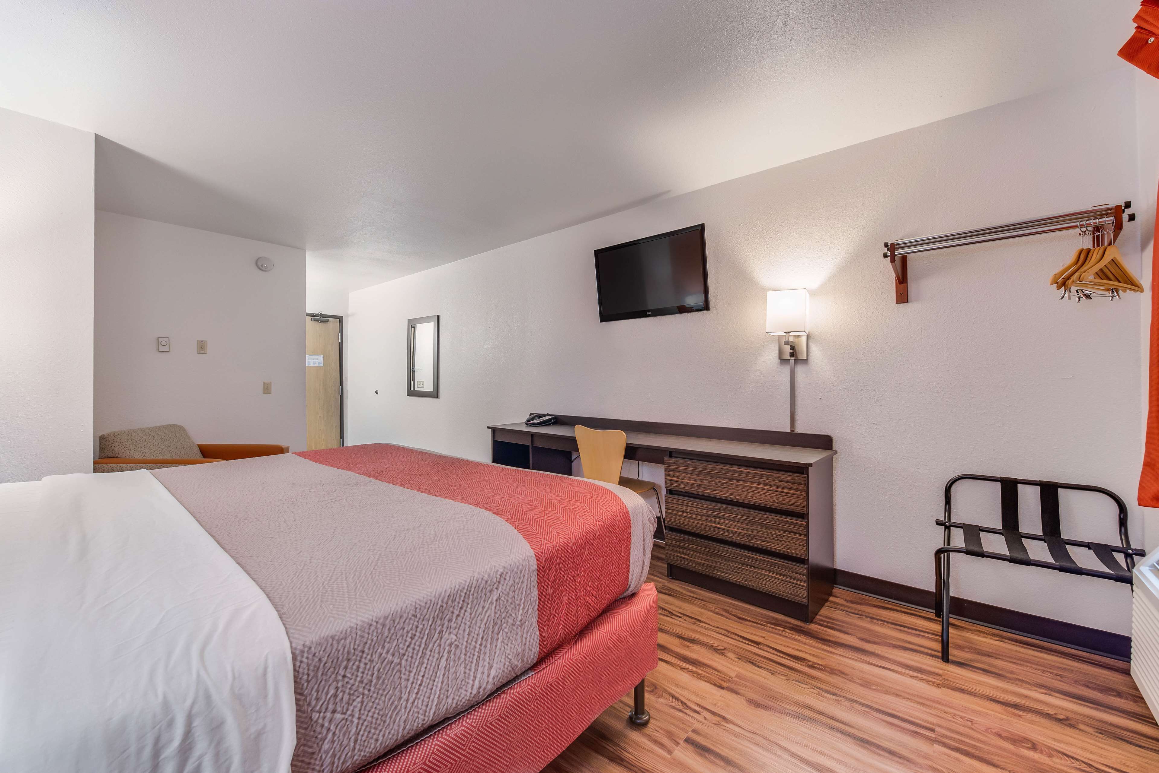Une chambre d’hôtel équipée d’un lit, d’un bureau, d’une chaise, d’une télévision et d’un porte-manteau.