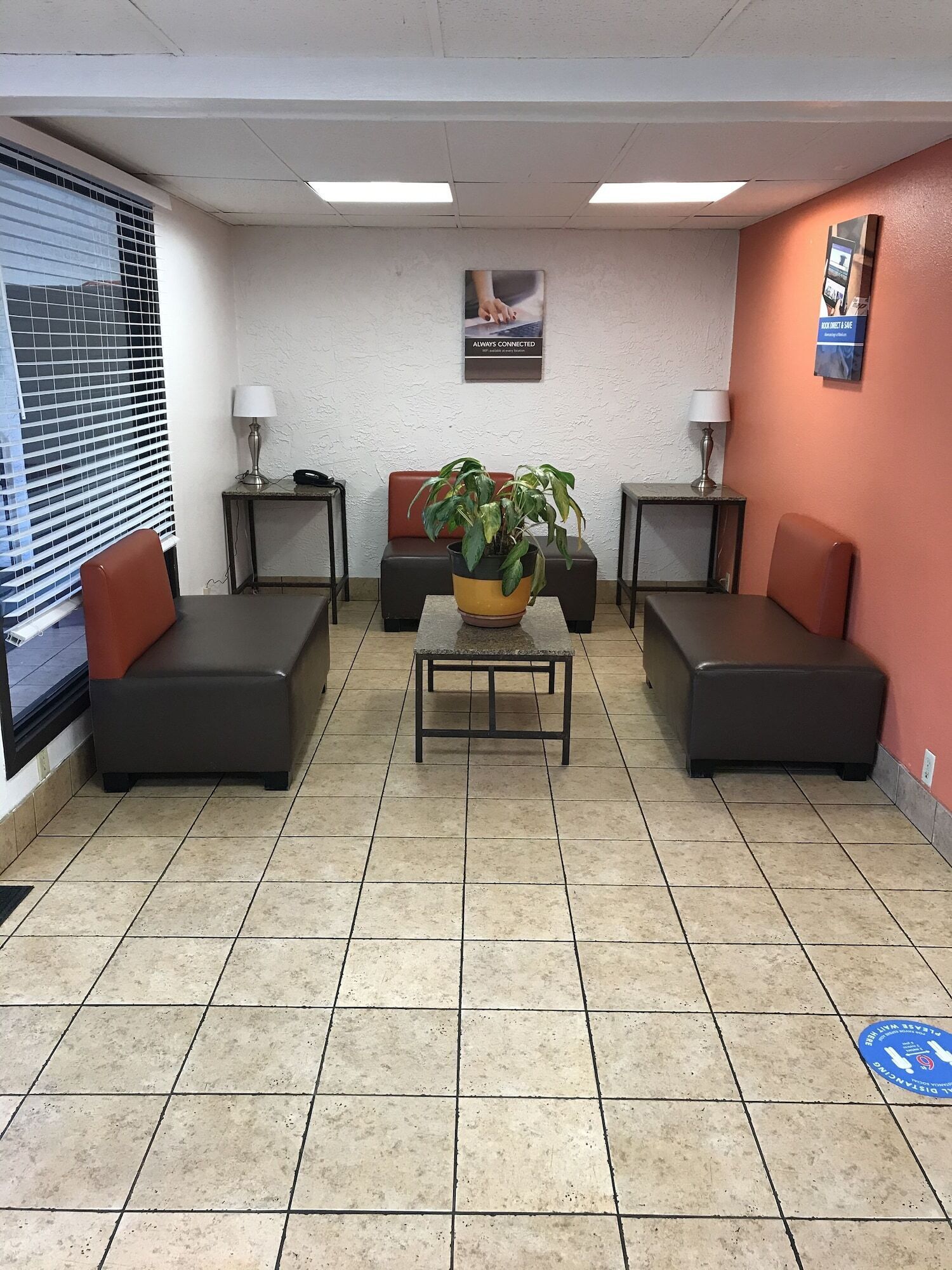 Un espace d’attente comprenant quatre canapés noirs, une table basse centrale et une plante en pot.