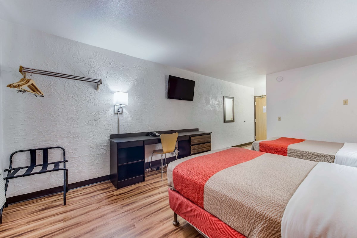 A hotel room with a bed, a desk, a chair, a TV, and a wardrobe.
