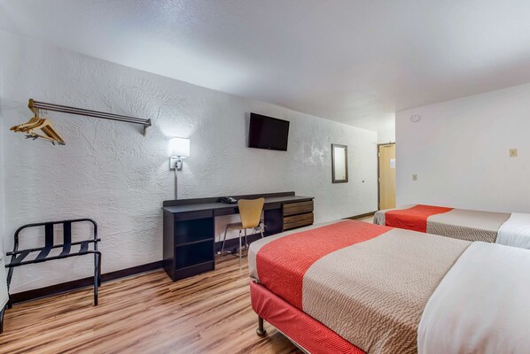 Una habitación de hotel con cama, escritorio, silla, televisor y armario.