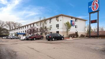 A motel with a large sign, a parking lot, and several cars parked in front.