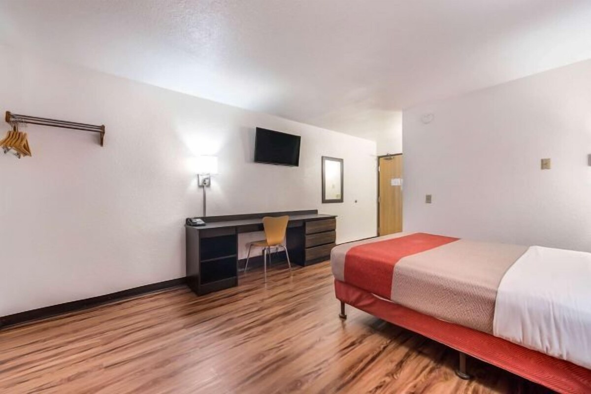 A bedroom with a bed, a desk, and a chair.