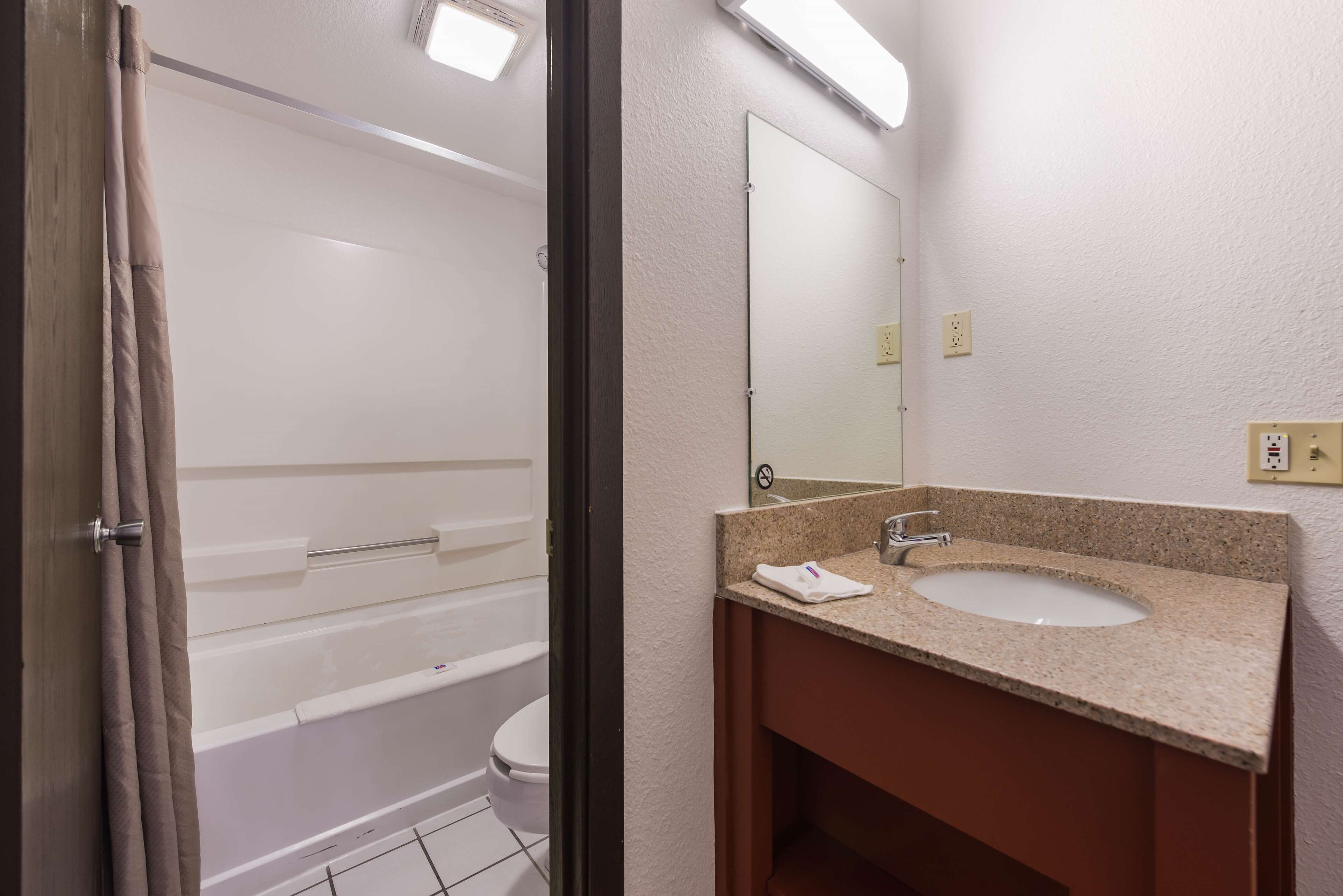 A bathroom with a bathtub, toilet, sink, and mirror.
